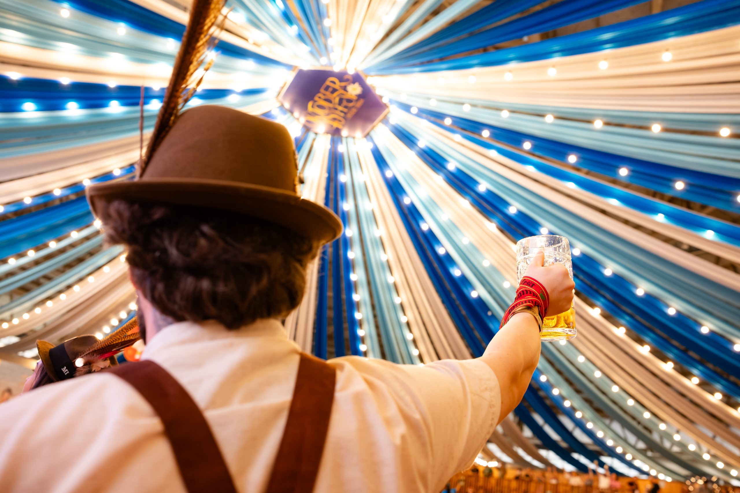 Brinde de chope sob a decoração azul e branca da Oktoberfest Blumenau